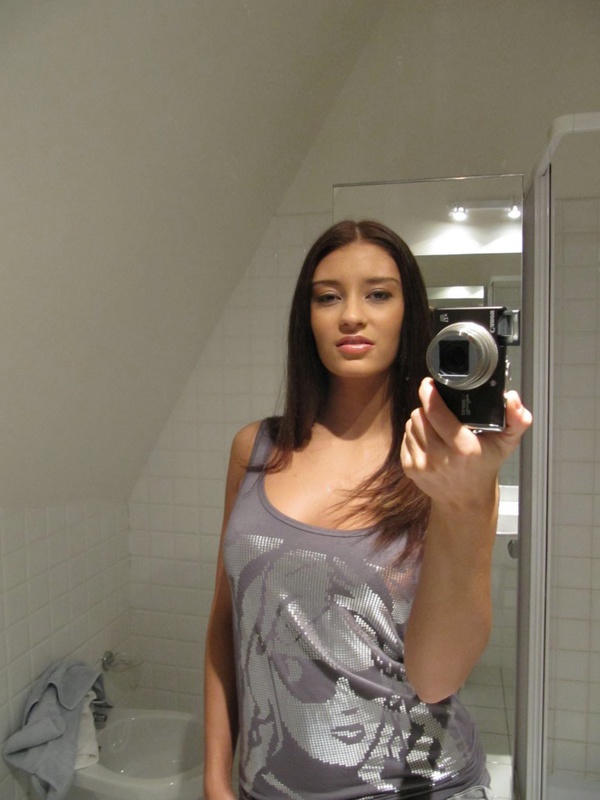 Обнаженная темноволосая девчонка с камерой в ванной
