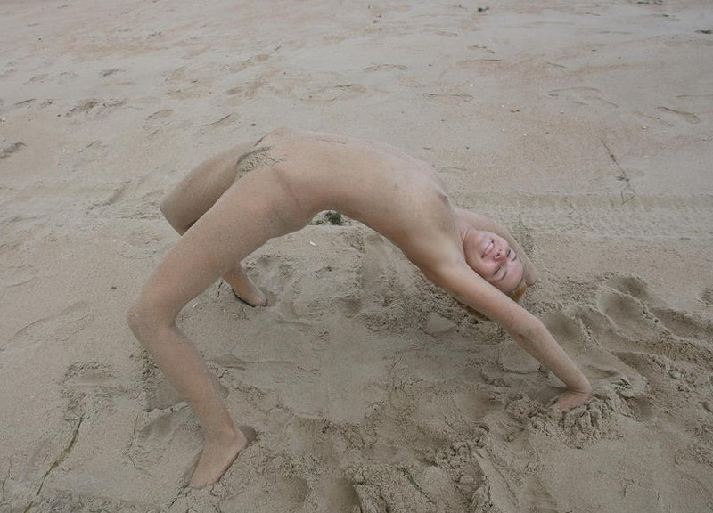 Стройная молодая девица голая позирует на пляже
